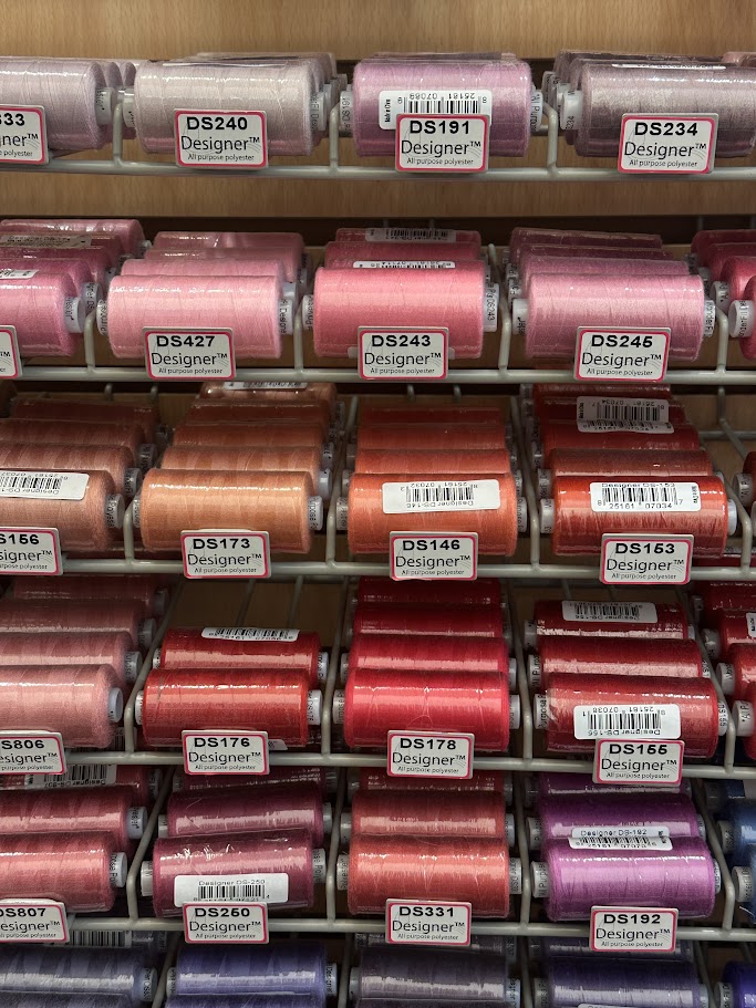 Spools of thread in pink, orange, red and purple colorways.